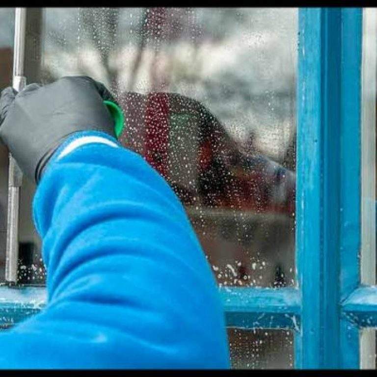persona limpiando con guantes una ventana